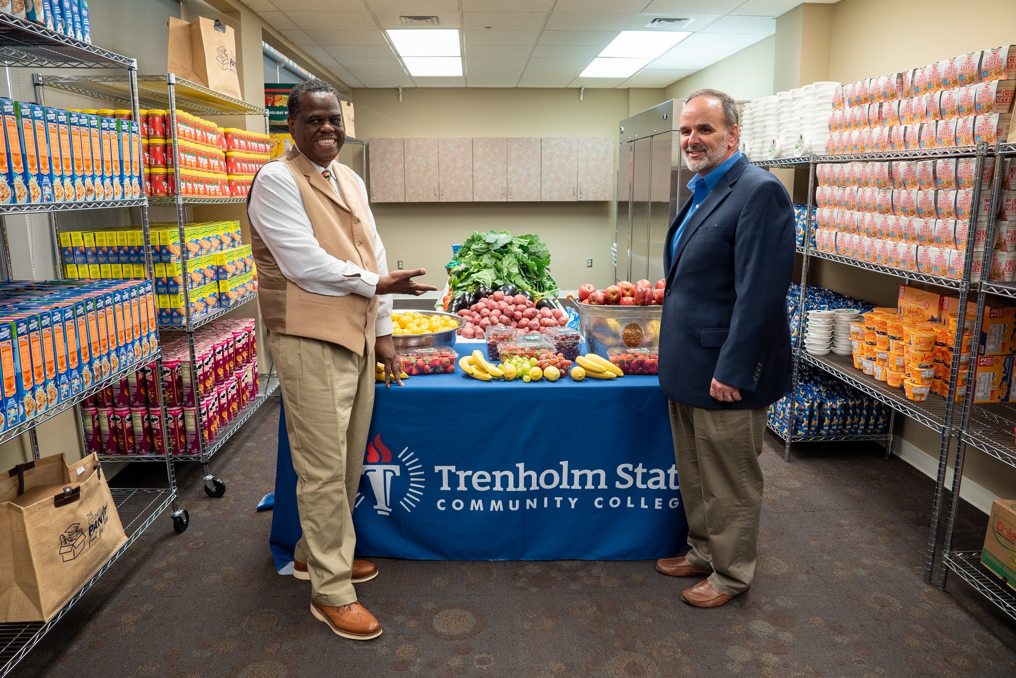 two men standing next to a table with fruits